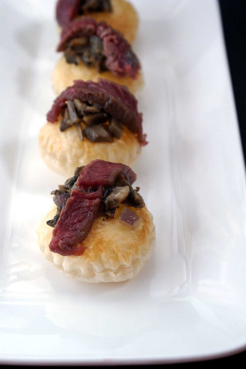 De-constructed Beef Wellington Canapés. Puff pastry disks topped with a mushroom duxelle and a slice of fillet steak. 