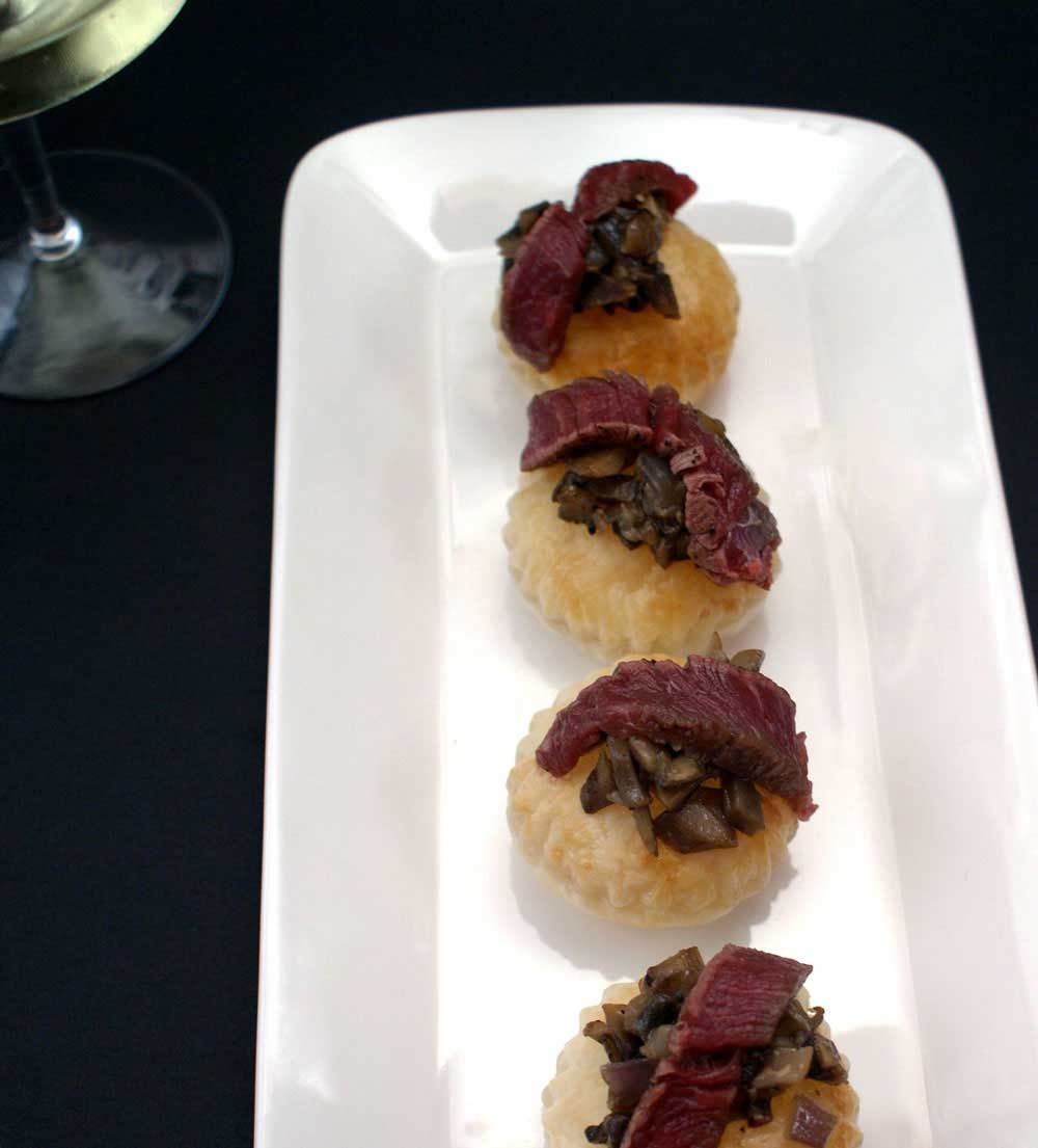 De-constructed Beef Wellington Canapés. Puff pastry disks topped with a mushroom duxelle and a slice of fillet steak. 