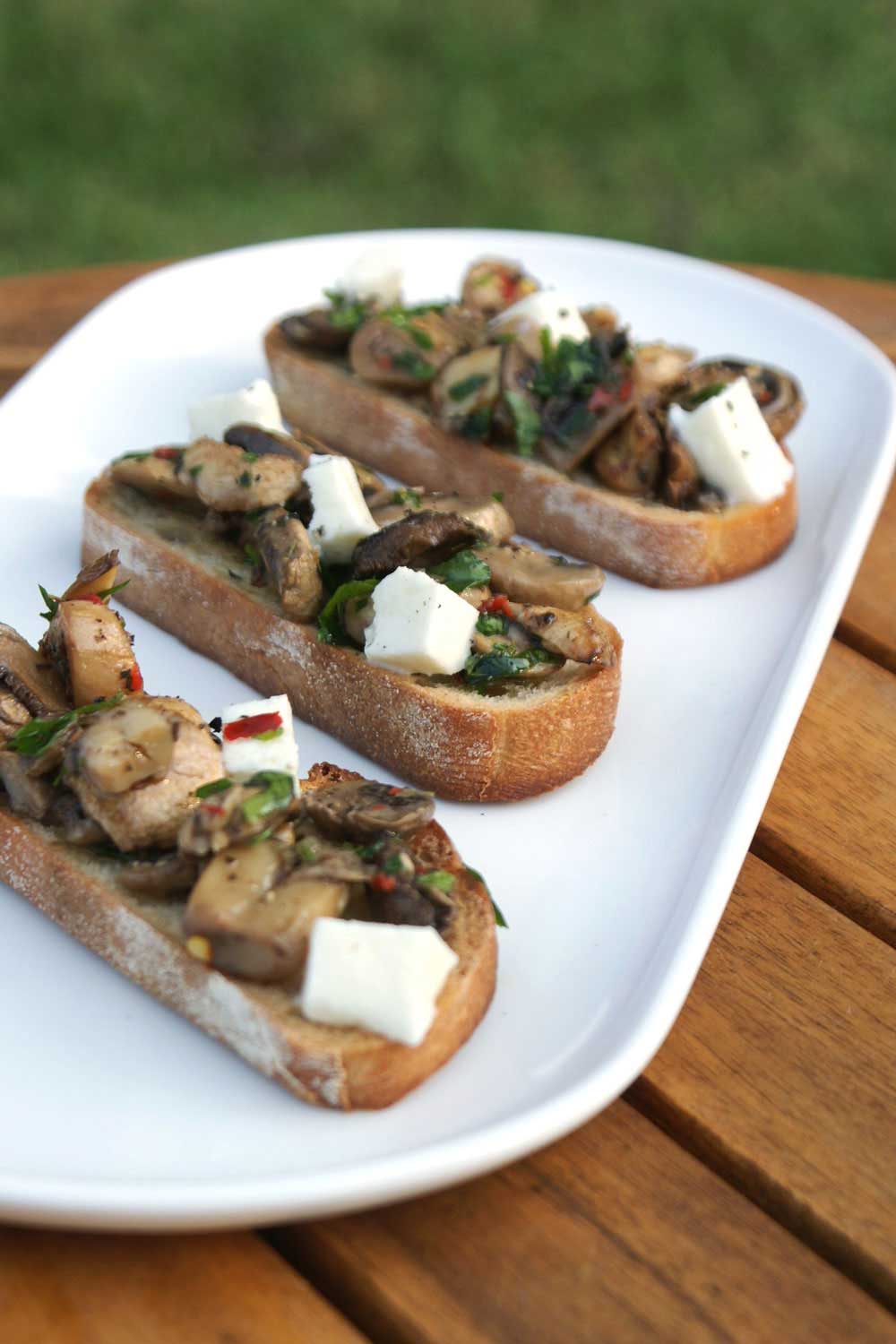 Mushroom Bruschetta. Crisp crostini topped with mozzarella and garlic and parsley cooked mushrooms. A perfect appetizer, great with a glass of wine or a cold beer. 