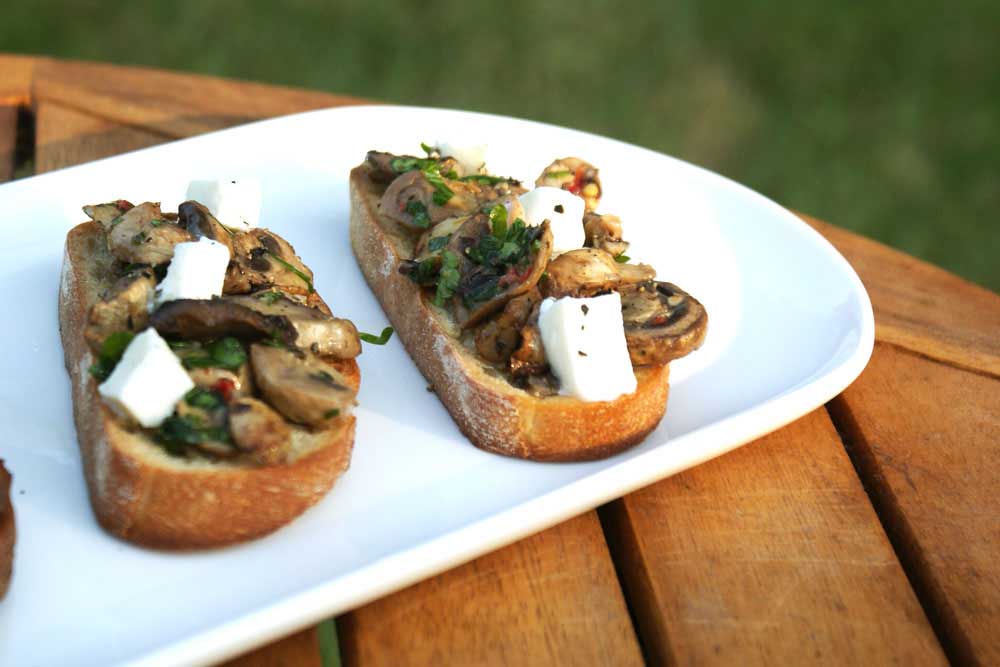 Mushroom Bruschetta. Crisp crostini topped with mozzarella and garlic and parsley cooked mushrooms. A perfect appetizer, great with a glass of wine or a cold beer. 