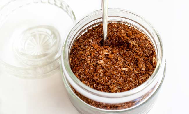 glass jar of steak rub with a glass lid to the left