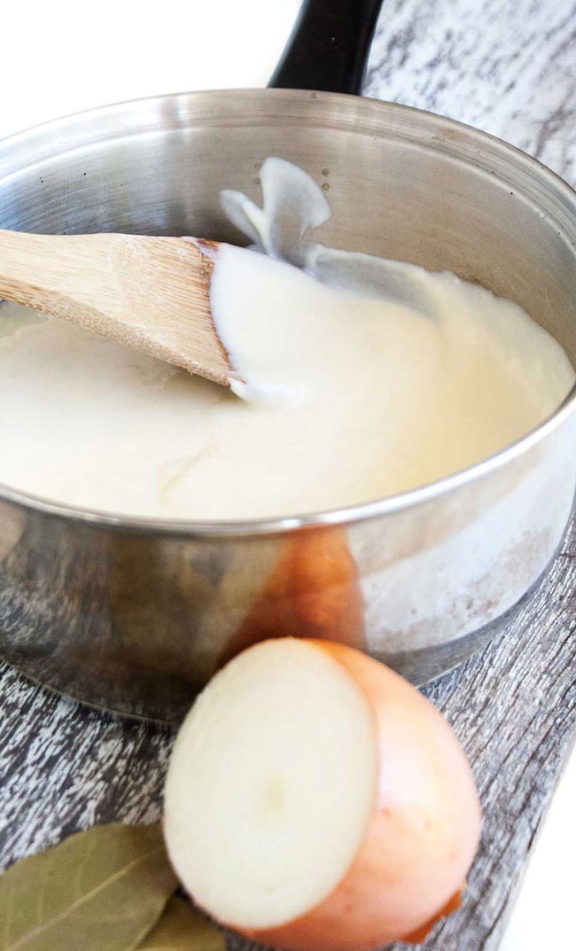 Close up showing the smooth creamy white sauce on a wooden spoon.