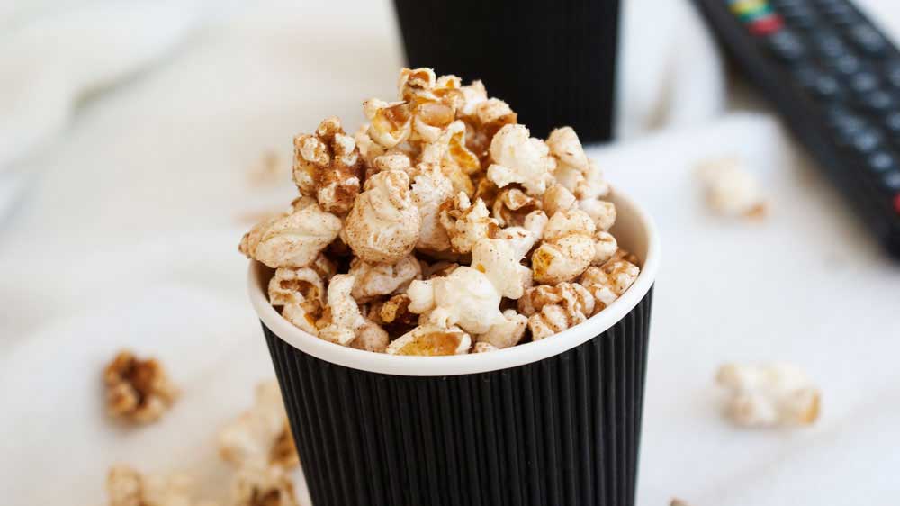 close up on some cinnamon sugar popcorn in a black cup