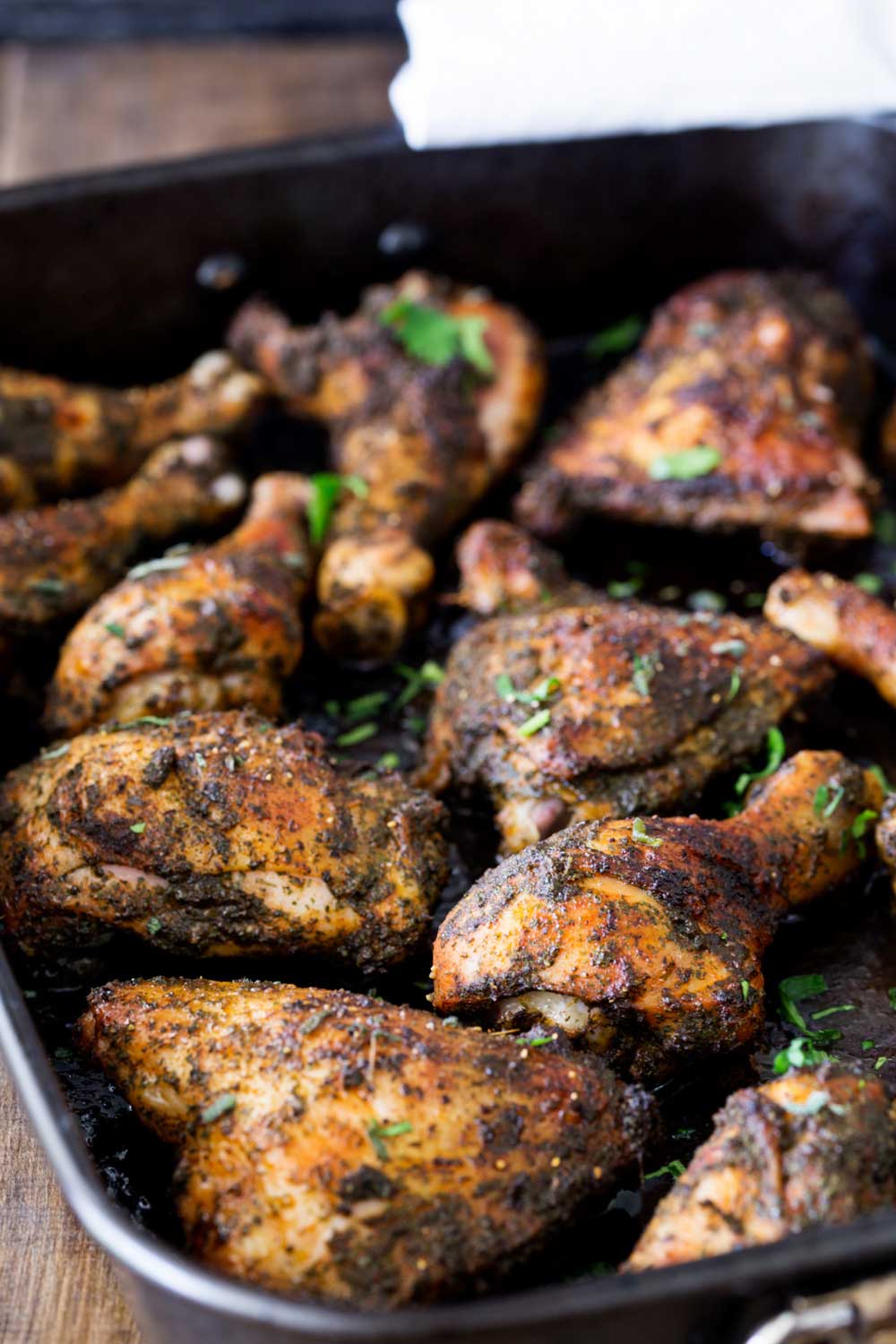a black baking tray filled with roasted chicken pieces