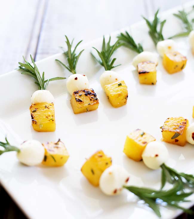 Mozzarella Balls and cubes of pineapple, skewered onto rosemary skewers.