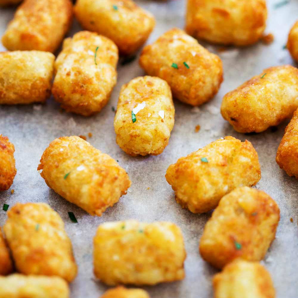 crispy brown cooked potato tots on a lined baking sheet