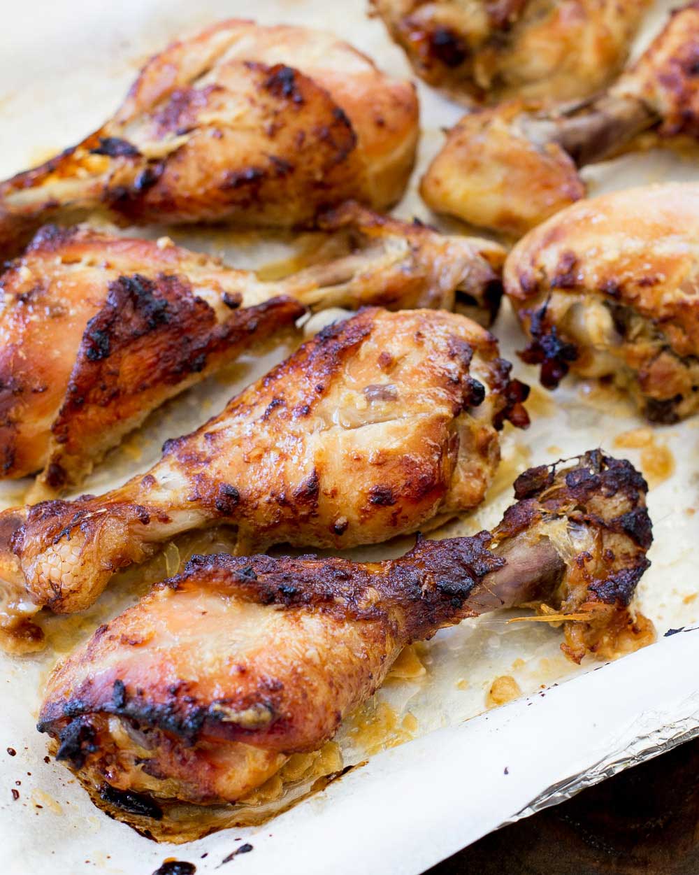 Baking tray with baked chicken drumsticks on it