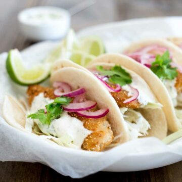 These fish tacos are taco heaven! Soft flour tortillas are filled with crispy fish, sweet and sour brown sugar onions and an amazing creamy taco sauce.