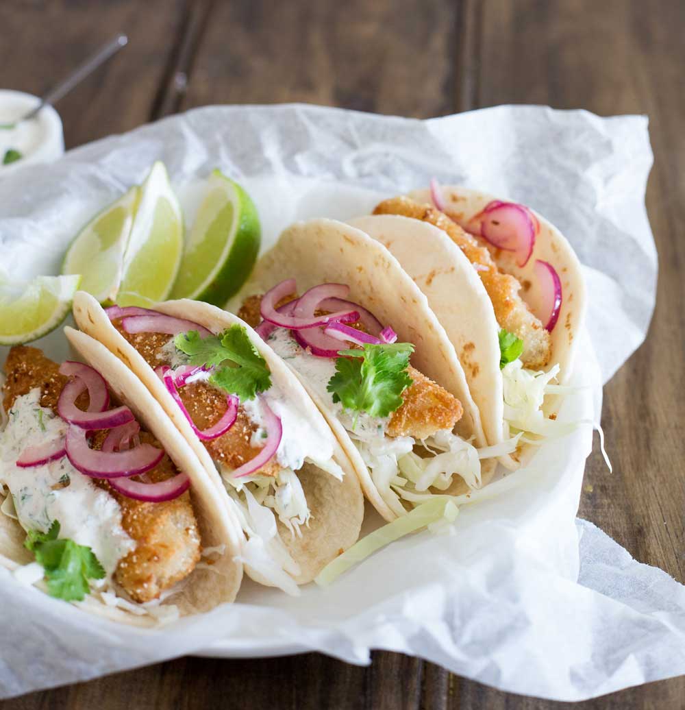 These fish tacos are taco heaven! Soft flour tortillas are filled with crispy fish, sweet and sour brown sugar onions and an amazing creamy taco sauce. 