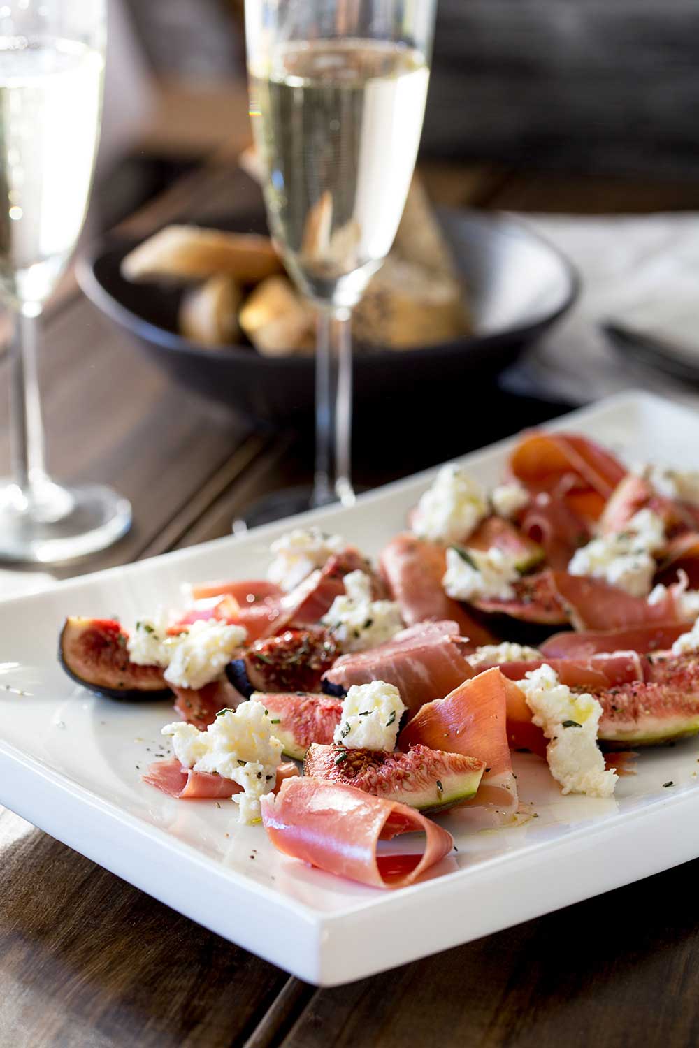Rustic table set with fig salad, crusty bread, and prosecco