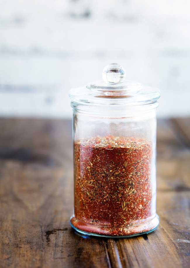 A tall jar filled with red creole seasoning
