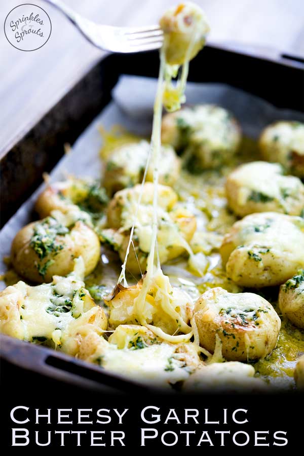 squashed garlic butter potatoes in a metal roasting tin, smothered with cheese