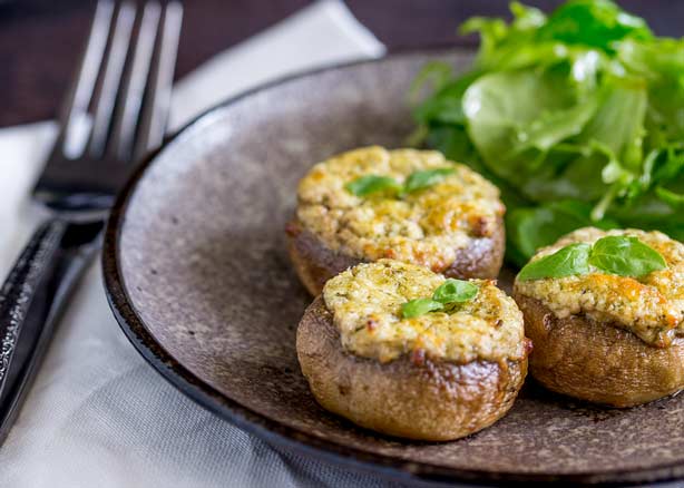 Small thumbnail picture of 3 basil and cheese stuffed mushrooms on a grey plate with a side salad.