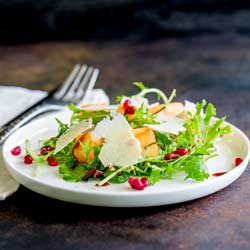 Square picture of melon and pomegranate salad on a shallow white plate.