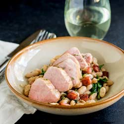 Succulent pork sat on a bed of creamy beans and crispy salty bacon. This Pork Tenderloin with Beans and Bacon delicious, comforting and oh so simple to make. Plus it looks elegant, which makes it perfect for entertaining. Recipe from Sprinkles and Sprouts | Delicious food for easy entertaining.