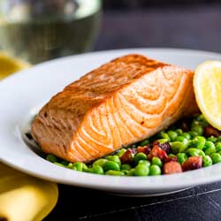 Succulent salmon with a crispy skin, sat on a bed of crushed sweet peas and spicy chorizo. This Seared Salmon with Peas and Chorizo is elegant yet simple. A perfect entree for entertaining. Recipe from Sprinkles and Sprouts | Delicious food for easy entertaining.