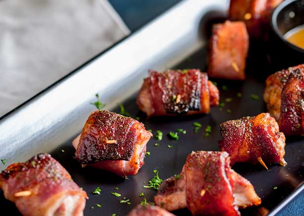 Brown Sugar Bacon Wrapped Chicken Bites on a black rectangular plate.