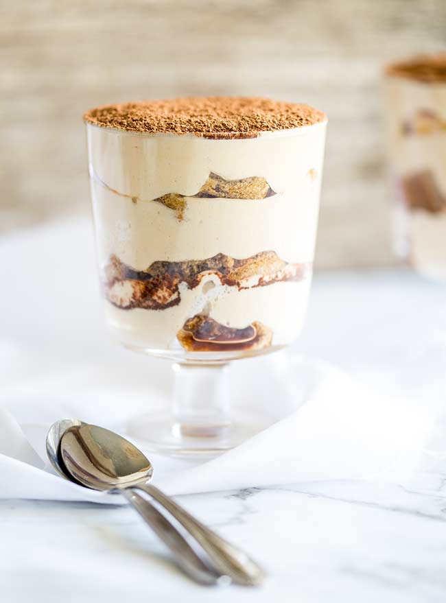 Individual tiramisu in a glass on a marble table. Clearly showing the layers in the dessert.