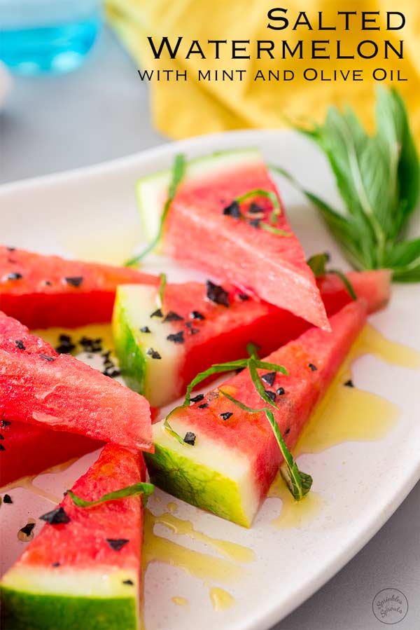 Stacked wedges of watermelon with black salt on them on a white plate.