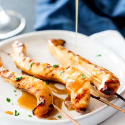 Sticky bourbon chicken skewers on a flat white plate.