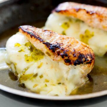 sq picture of two dill pickle and provolone stuffed chicken breasts in a frying pan.