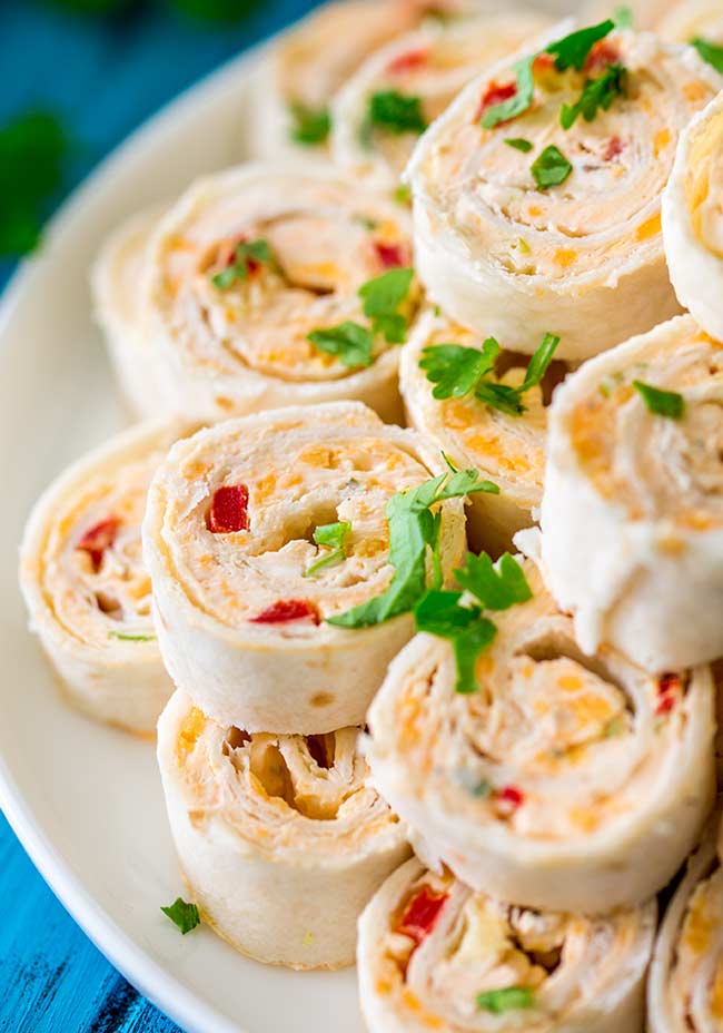 Overhead showing mexican pinwheels stacked on a white plate with cilantro scattered over them