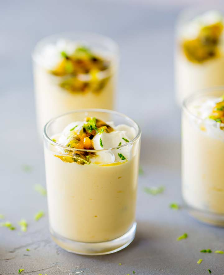 mini passionfruit cream pots, sat on a grey surface and garnished with lime zest