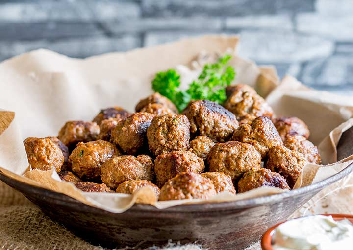 metal bowl lined with brown paper, piled with paprika meatballs and garnished with parsley