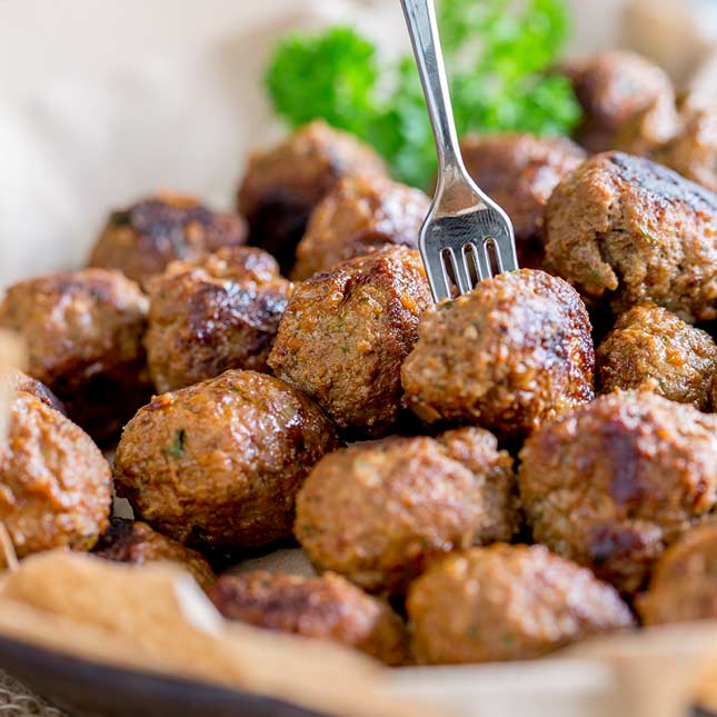 sq image showing a close up of a fork spearing a paprika beef meatball