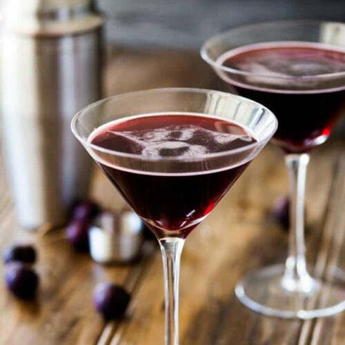 SQ shot showing two martini glasses with a dark red cherry martini in them