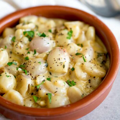 Ceramic bowl filled with creamy pearl onions garnished with parsley