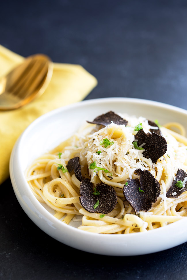 close up of black truffle pasta in a small white shallow bowl