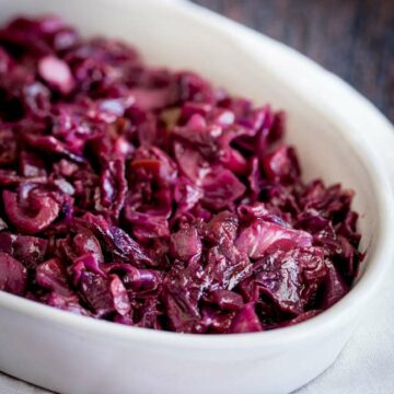 Close up on the chunky braised red cabbage in an oval serving dish on a wooden table