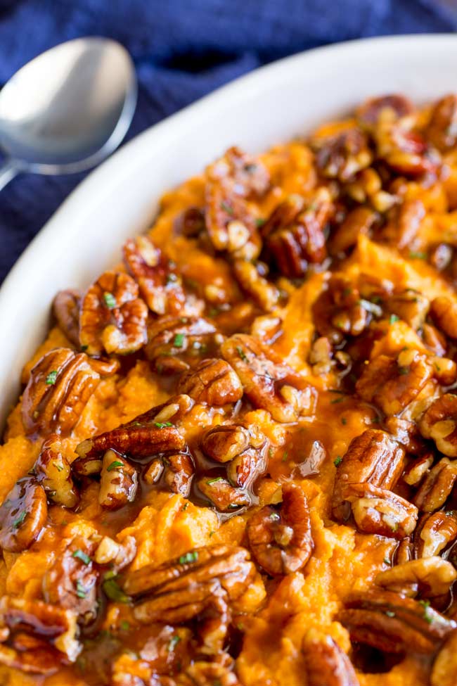 The topping of the sweet potato casserole topped with pecans and rosemary drizzled with maple syrup