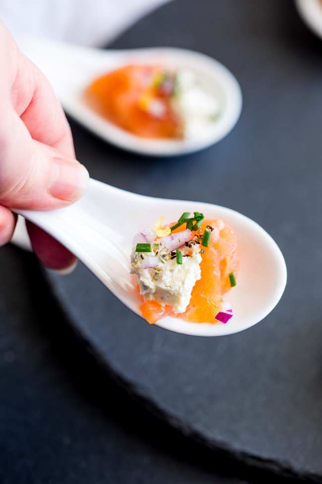 an amuse spoon of smoked salmon and cream cheese being picked up