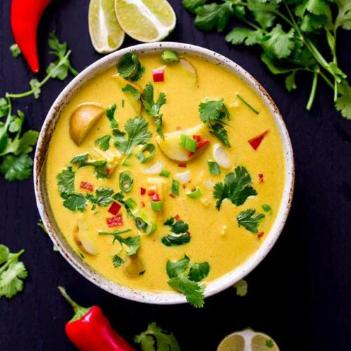 square picture showing an overhead view of the yellow soup in an earthenware bowl