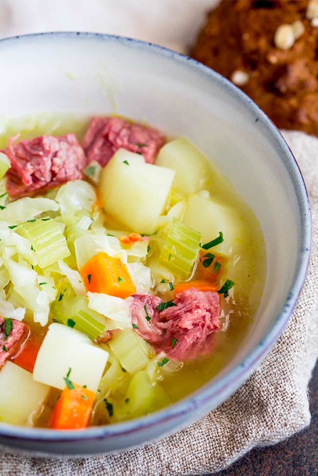 close up on the corned beef and cabbage soup in a light blue bowl