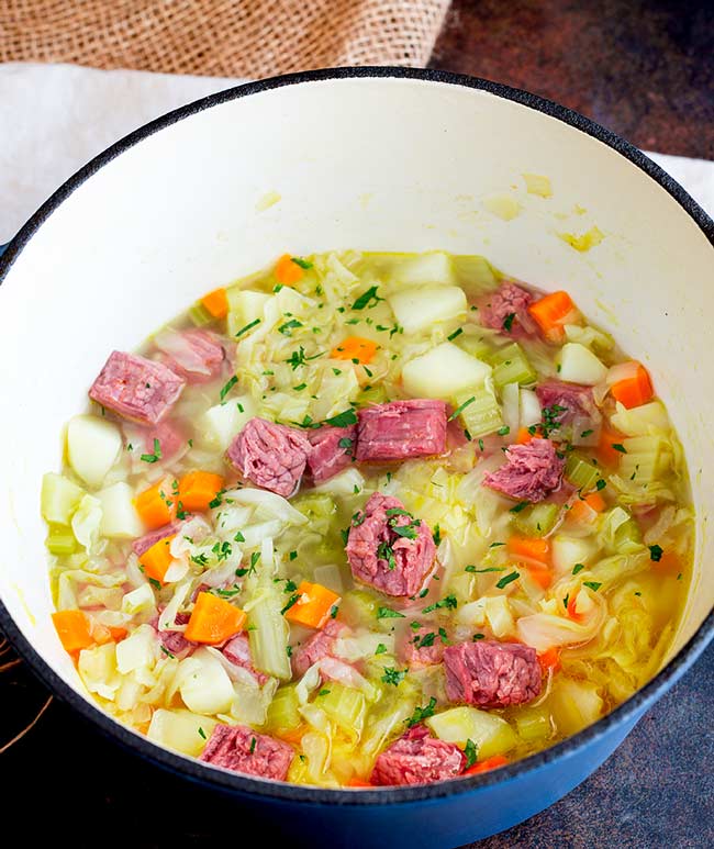 overhead shot of corned beef and cabbage soup  in a blue dutch oven