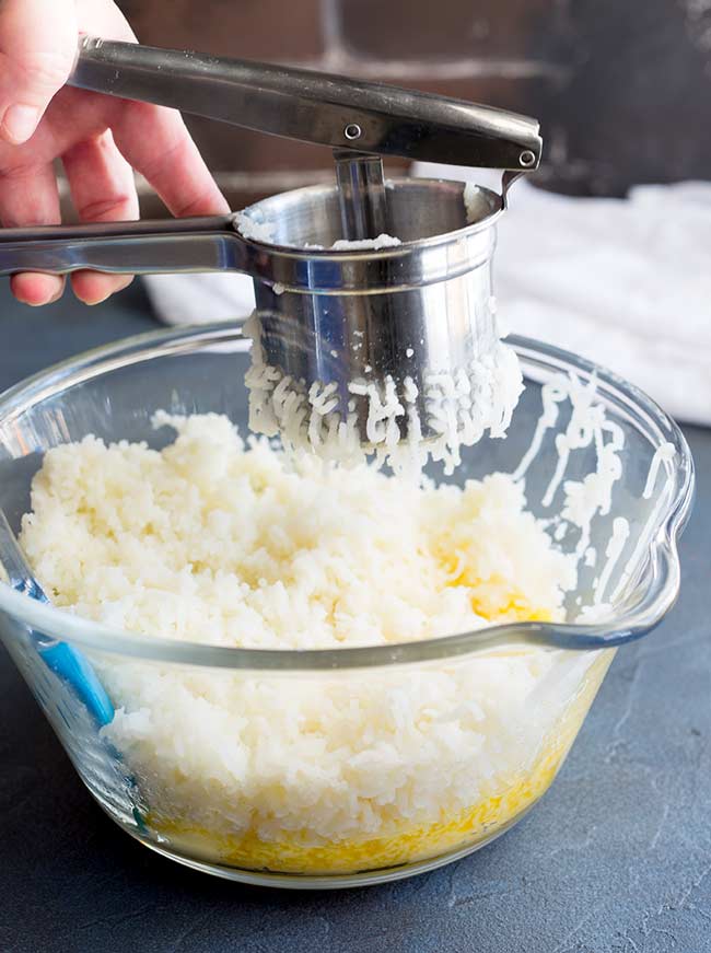 a potato ricer being used to make mashed potatoes