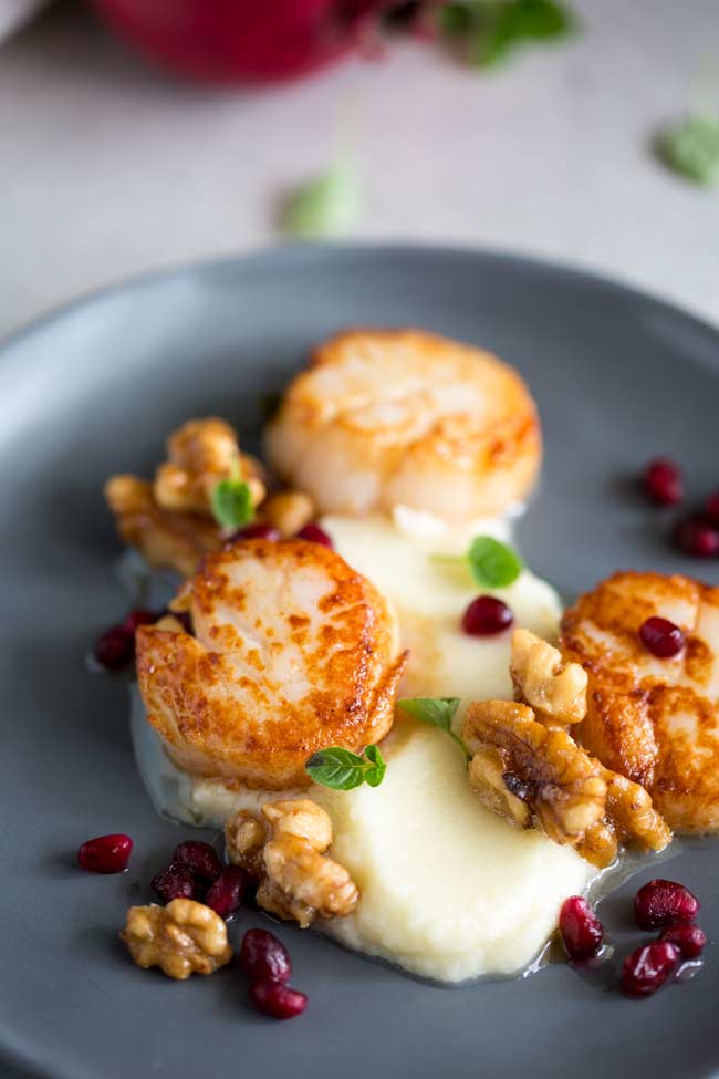 3 seared scallops on a bed of cauliflower puree with walnuts and pomegranates