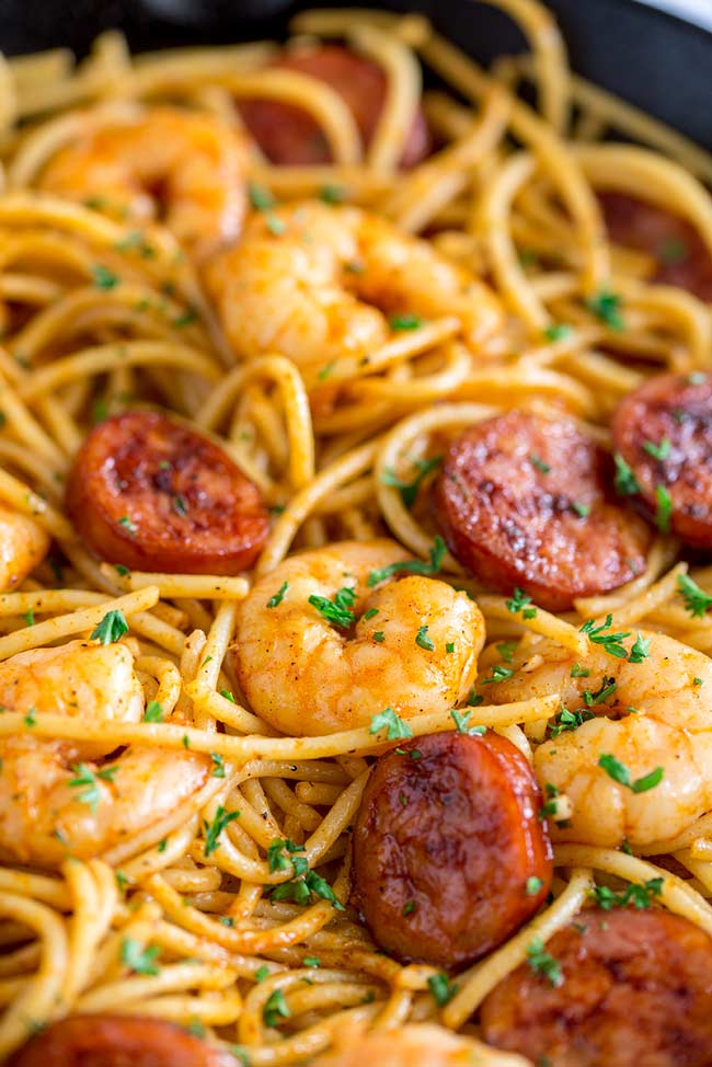 close up on the shrimp and chorizo in the fry pan full of pasta.