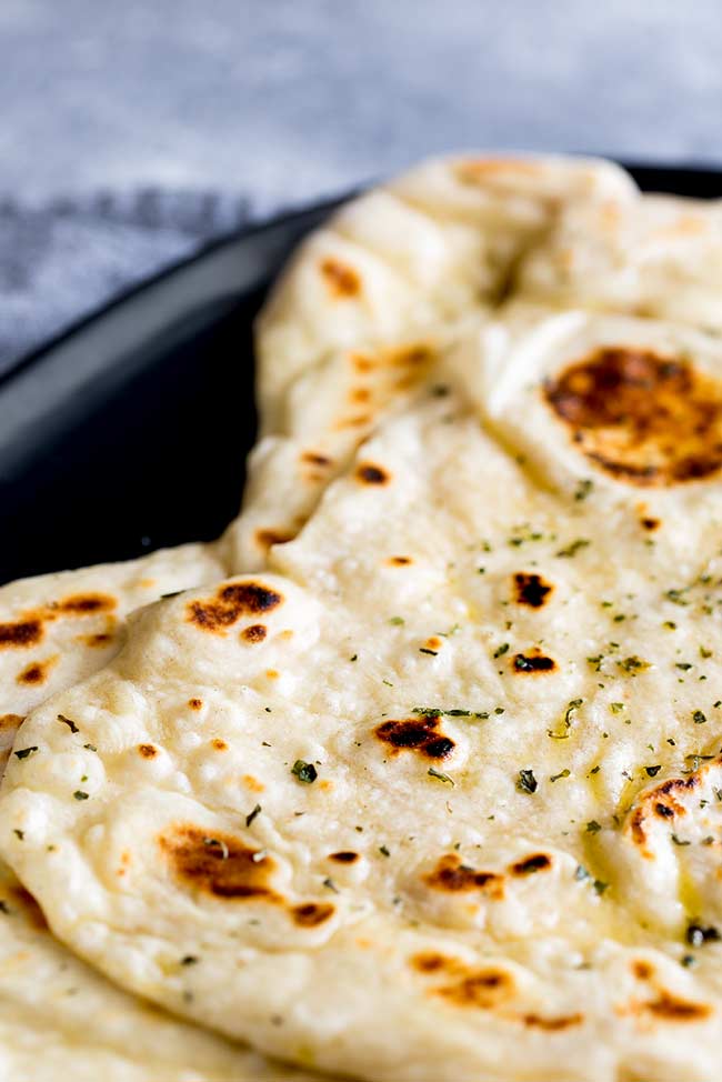 2 garlic naan breads on a black oval plate