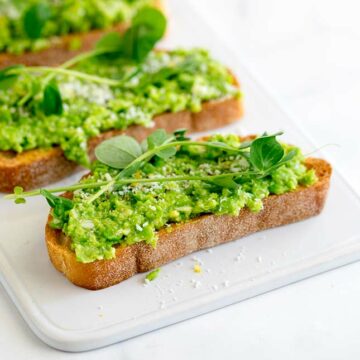 a white tray style plate with a pea bruschetta on it