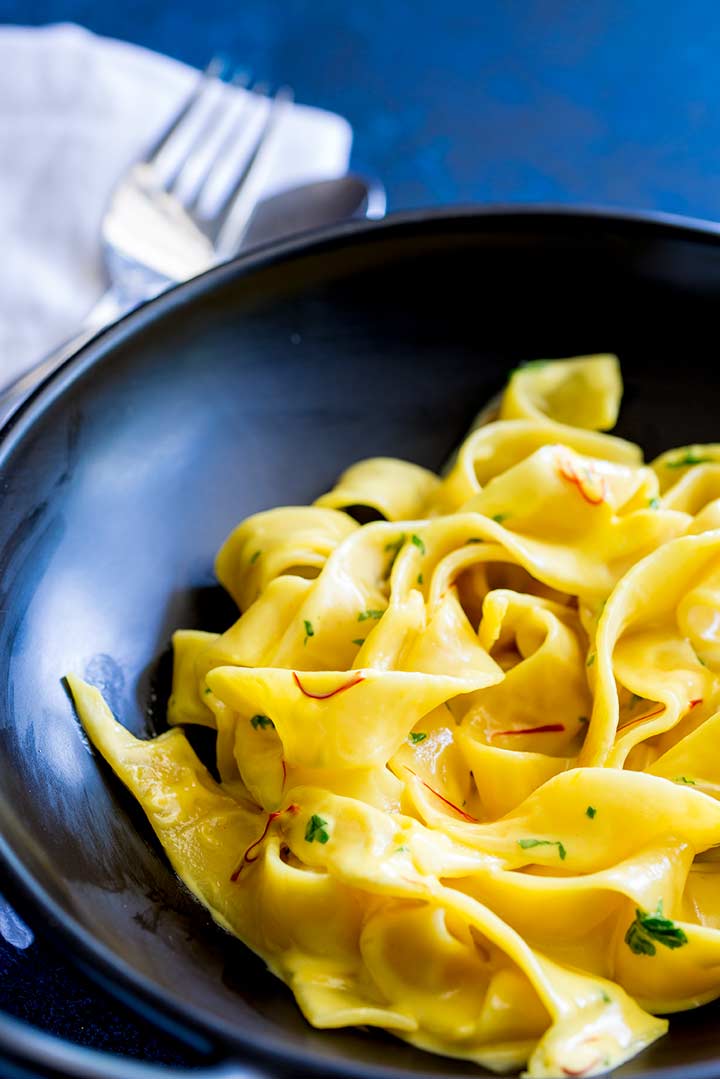 close up on the ribbon of pappardelle with a creamy saffron sauce