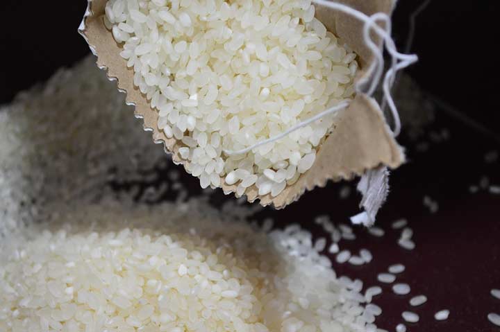 Risotto rice being tipped out of a paper bag onto a wooden table