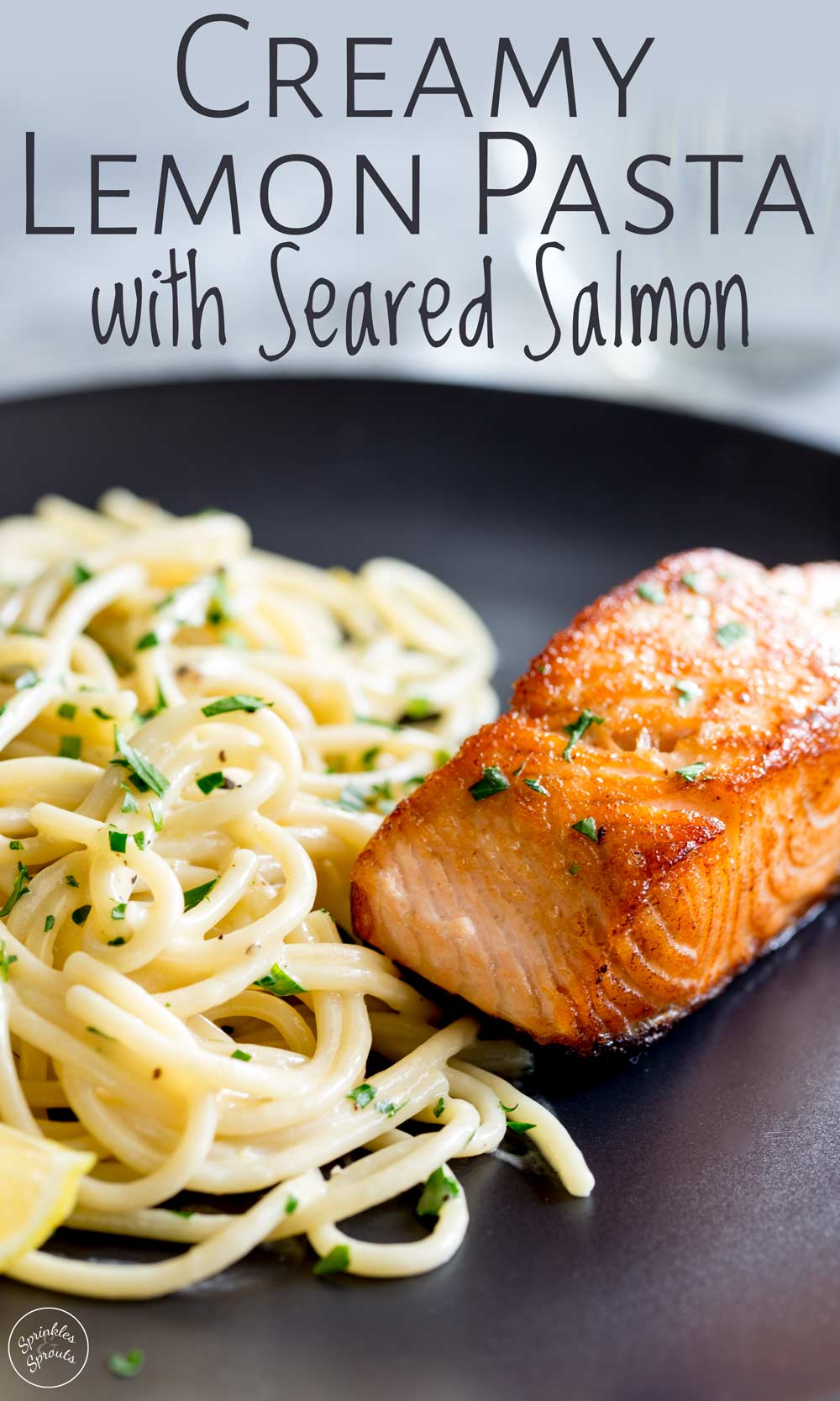 seared salmon and creamy pasta on a black plate with text at the top