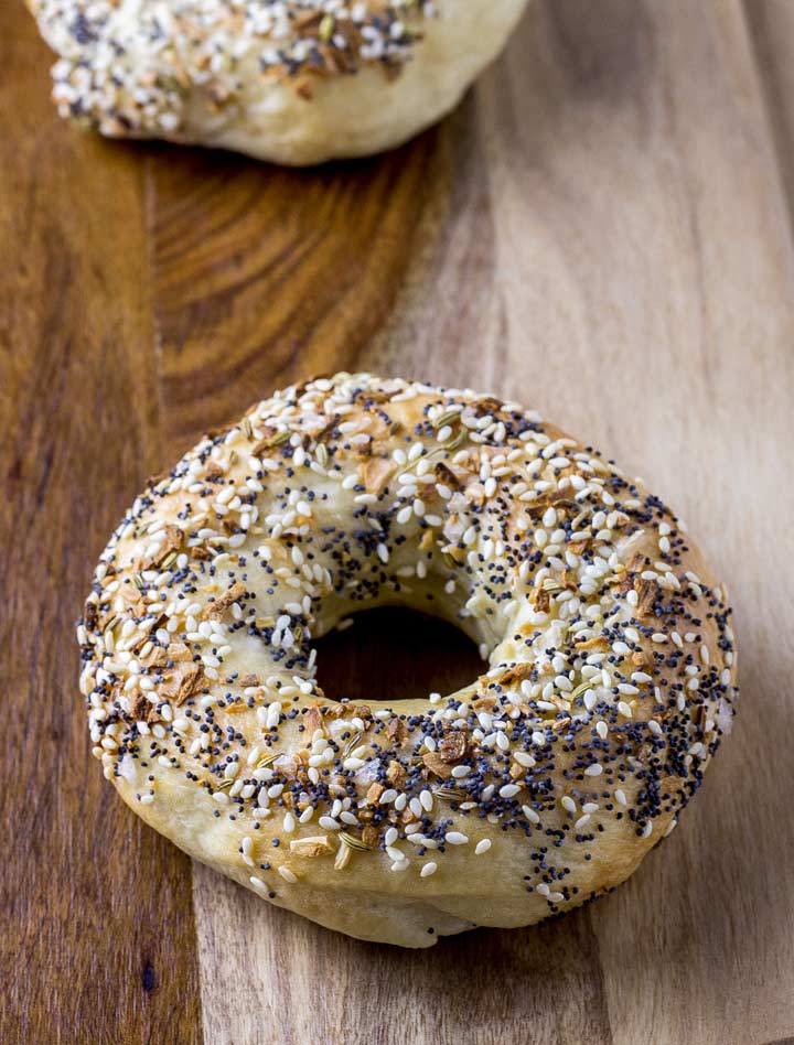 two everything bagels on a wooden board
