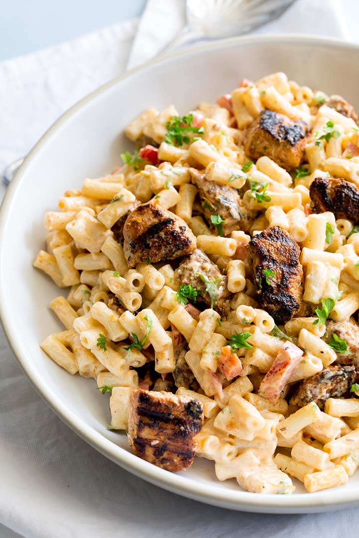 a white rustic bowl filled with macaroni pasta salad