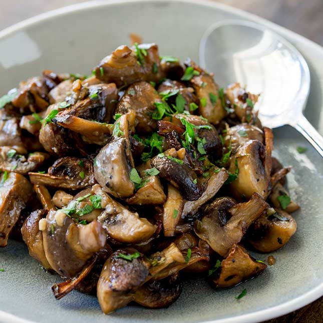 overhead view of roasted mushrooms on a grey plate