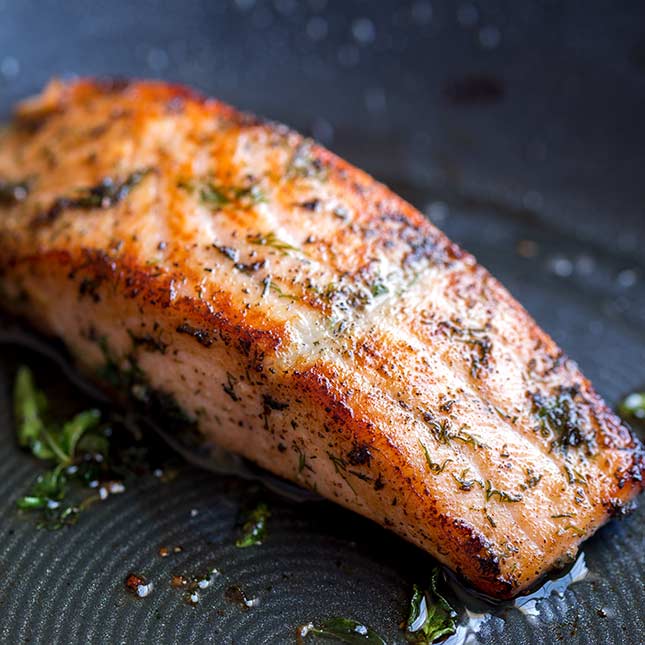close up on the seared salmon in a black pan